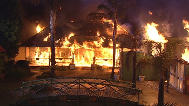 A screencap showing Lassiters complex on fire, particular Lou's Place.