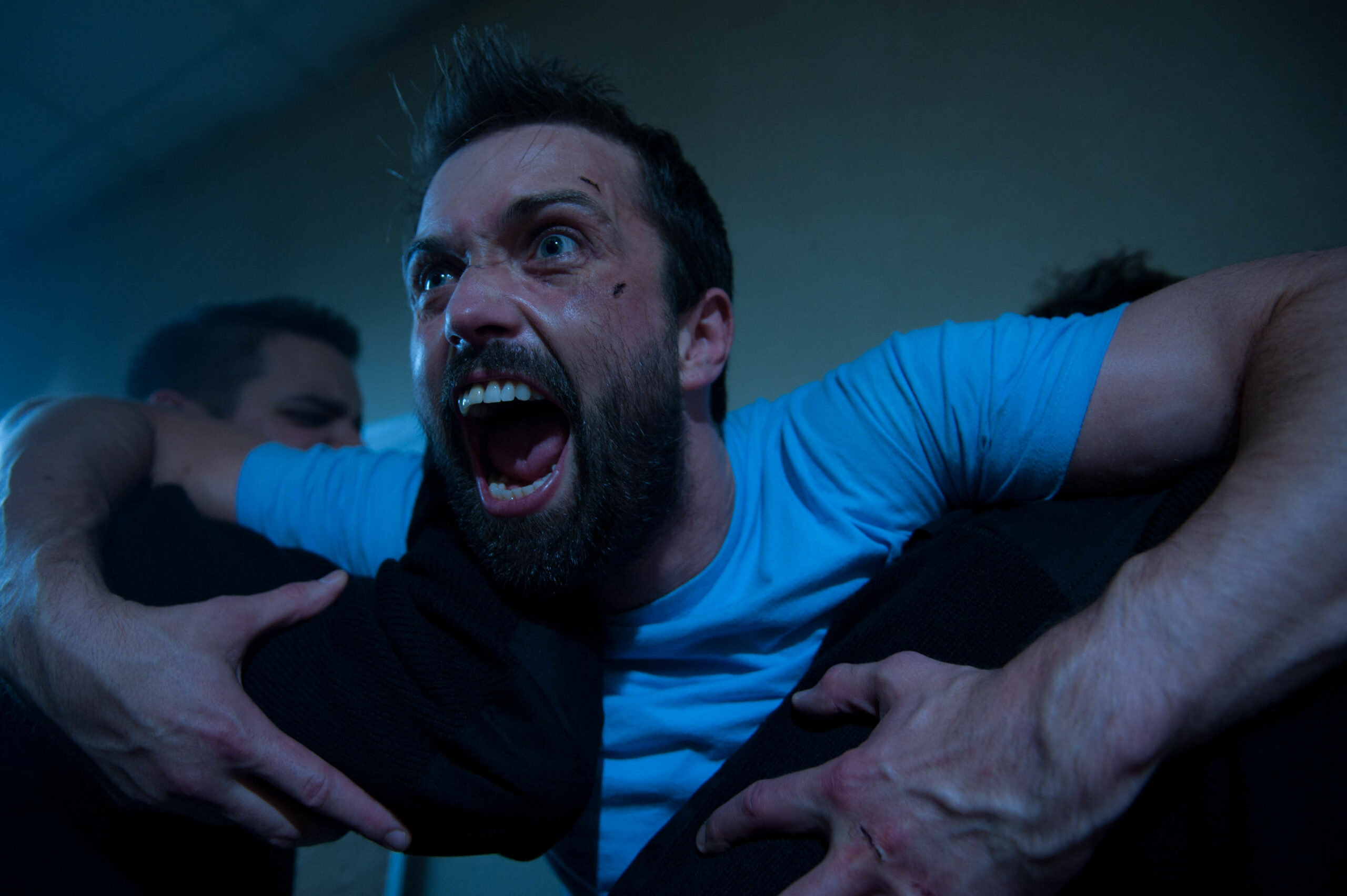 Brendan rages as he is restrained by two prison guards.