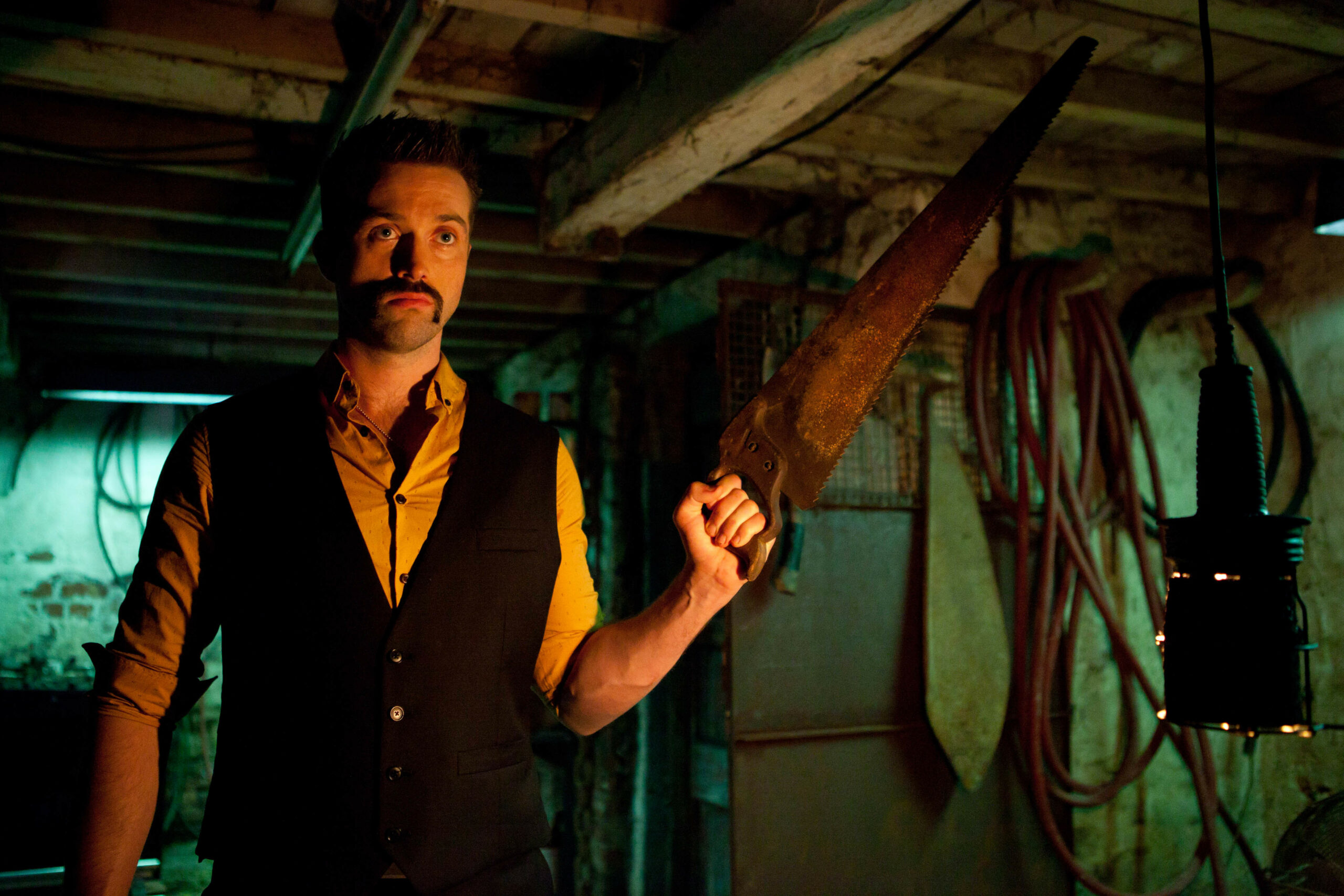 Brendan holds up a saw in a workshop.