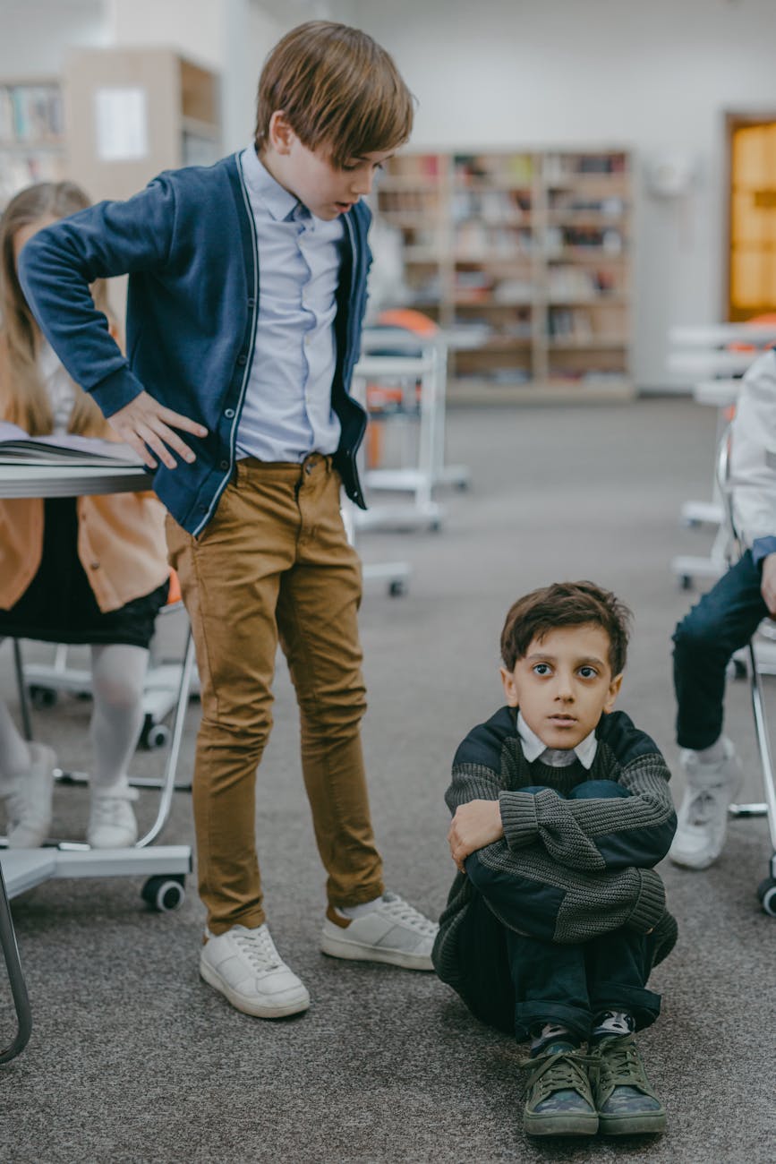 boy in blue jacket and brown pants standing with hands on his waist