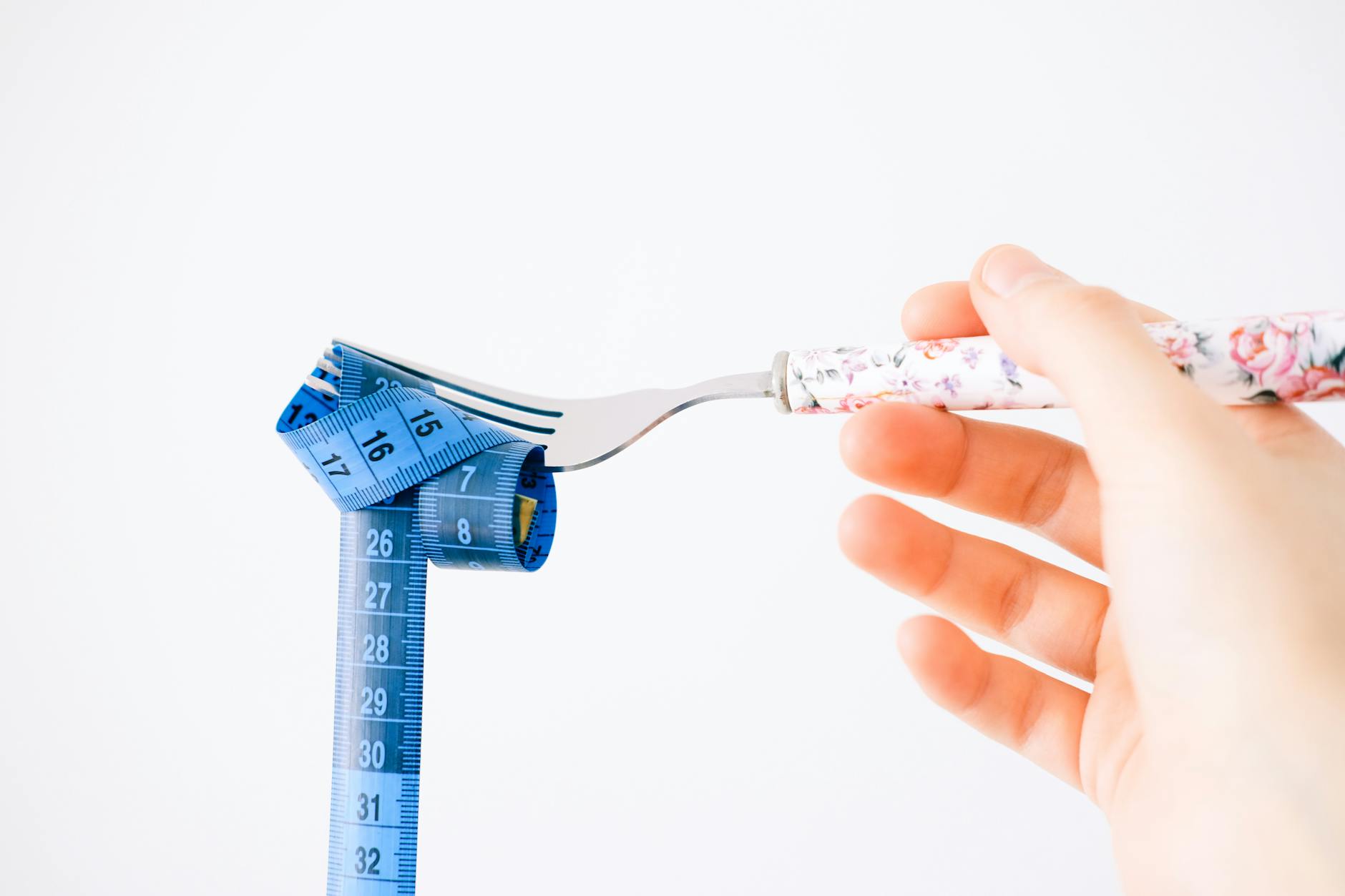 hand holding fork with wrapped measuring tape