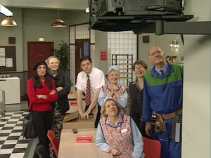 anita, twinkle, tony, jean, dolly, philippa and stan look up at a wall-mounted TV